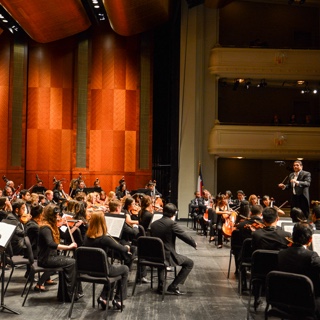 TCU maestro German Gutierrez directs a large group of musicians onstage at Bass Hall