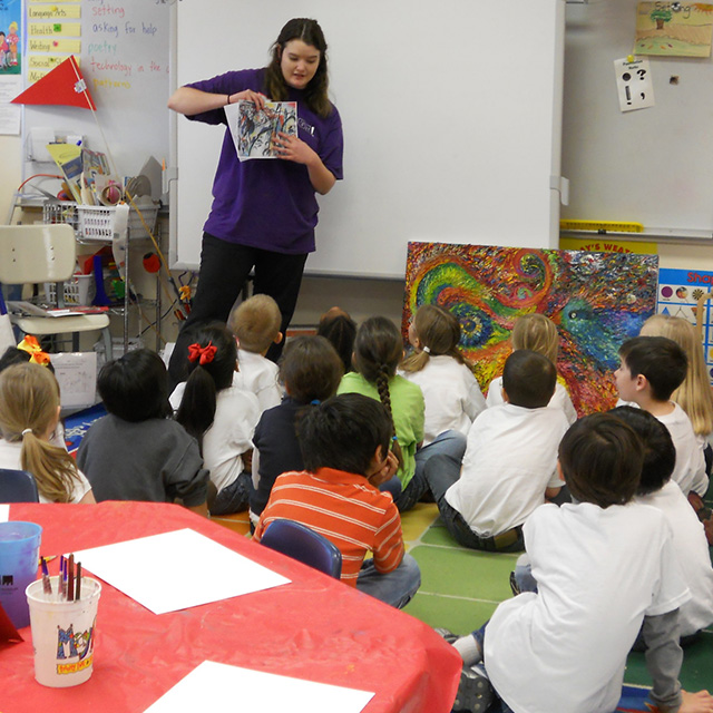 Art education student explains a painting to a group of elementary school children