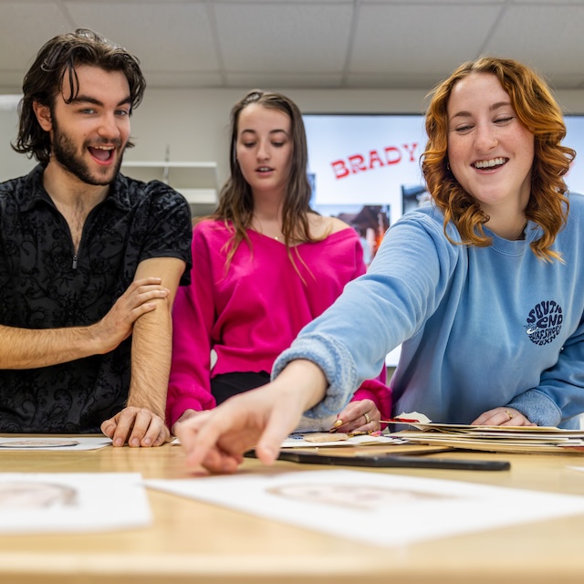 Three students review papers on table