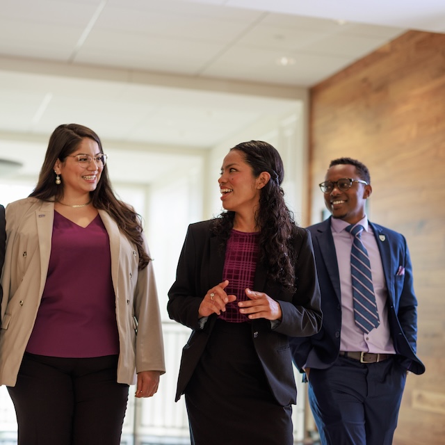 Three people in business suits walking and talking