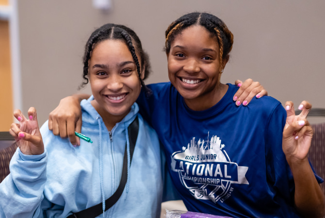 two girls showing the frog hand sign