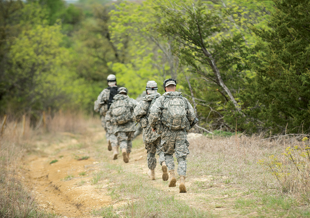 Army students run through the woods on a drill 