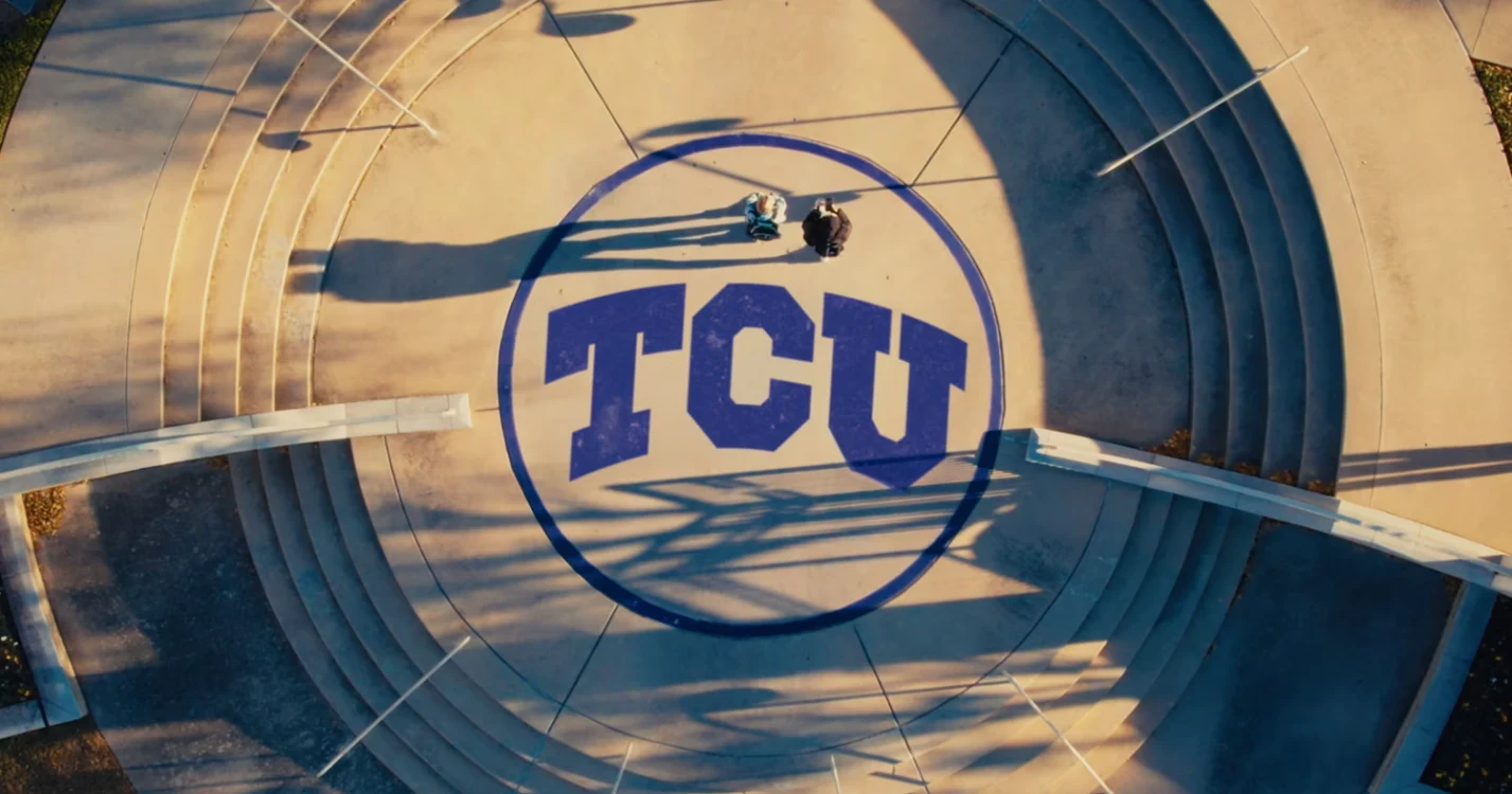 An overhead view of a circular concourse with a large TCU logo painted in the center